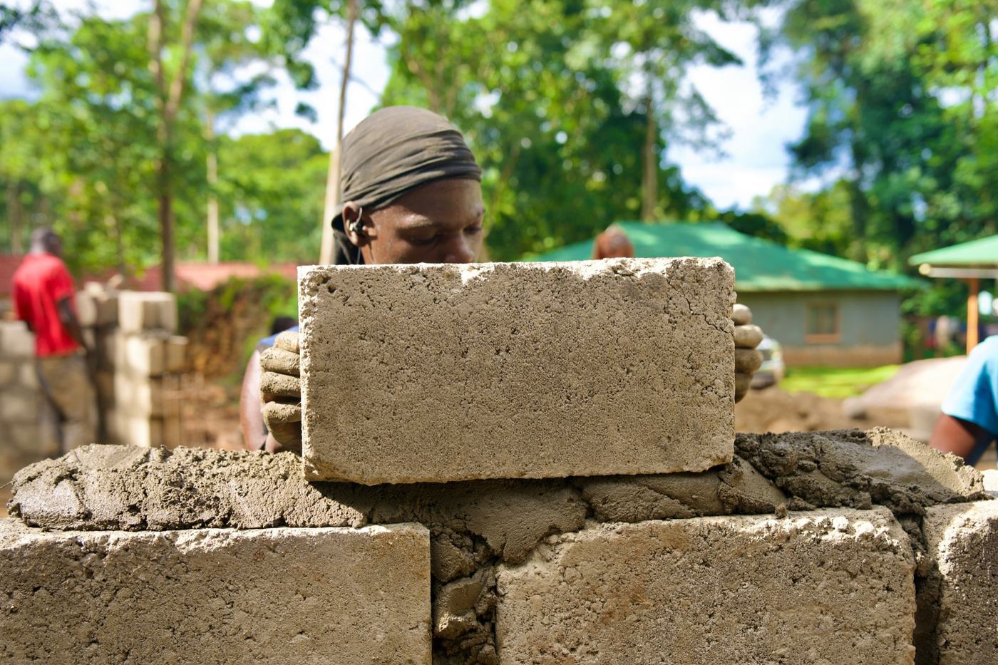 A builder laying concrete blocks for a community building