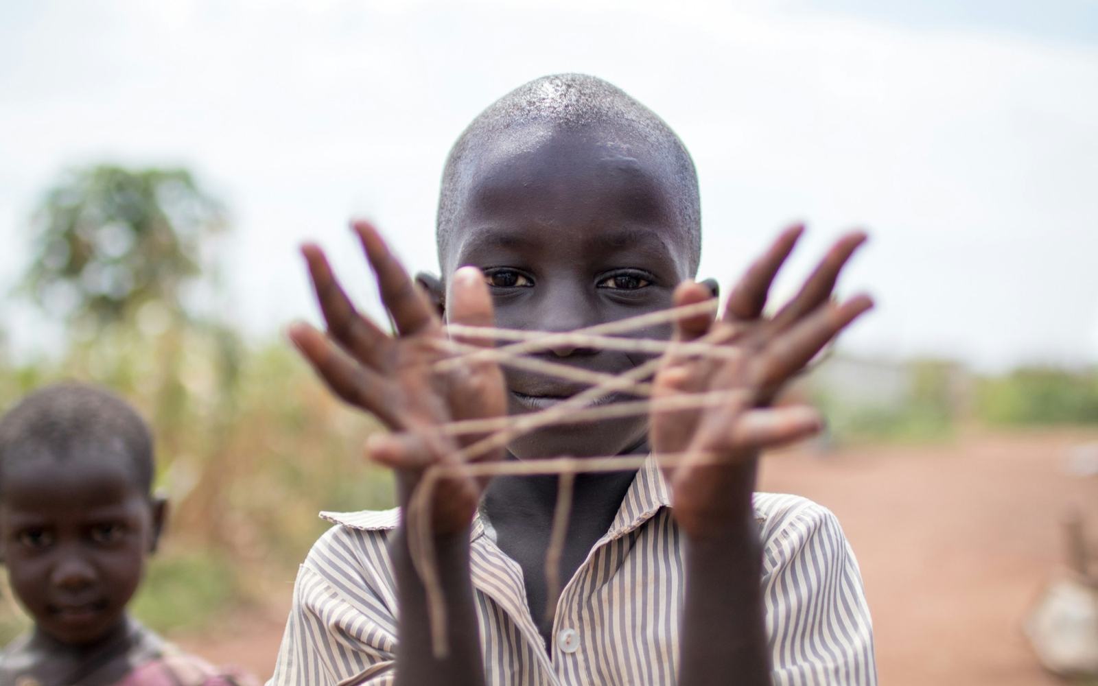 A boy making a string figure between his hands