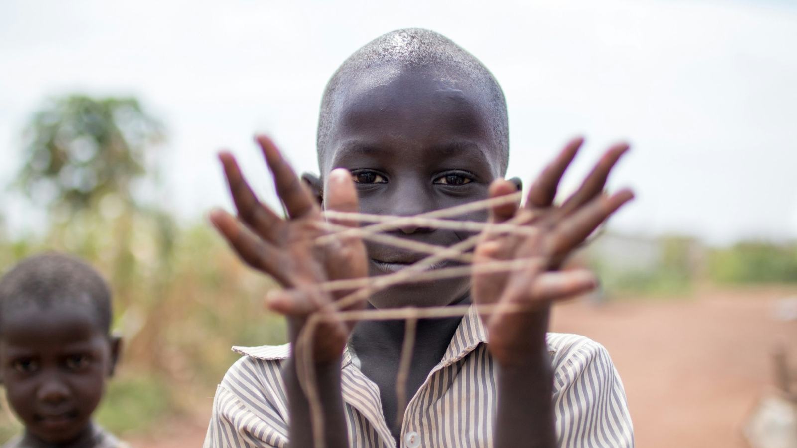 A boy making a string figure between his hands
