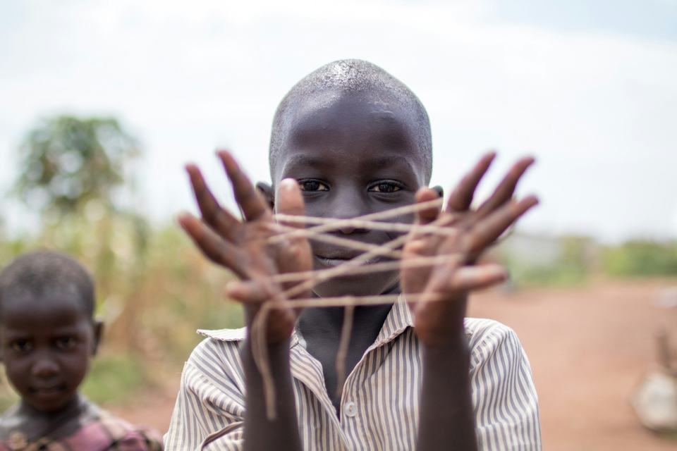 A boy making a string figure between his hands